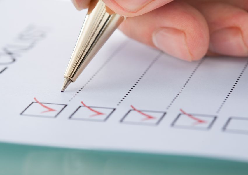 A paper move in inspection checklist is pictured as a property manager marks each box with a red checkmark.